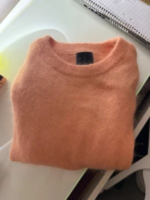 Korallfärgad stickad tröja - Mysig stickad tröja i korall färg. 70% Angora därför priset.