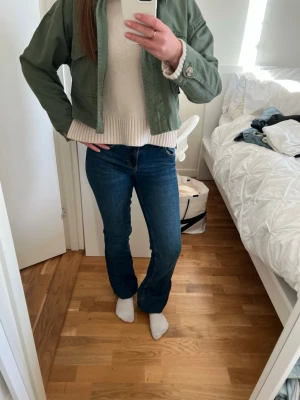 Mörkblå bootcut jeans - Snygga mörkblå bootcut jeans med klassisk femficksdesign och låg midja. Jeansen har en tidlös tvätt och är tillverkade i ett stretchigt denimtyg som sitter bekvämt. Perfekta för en avslappnad och trendig look.