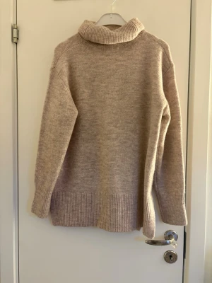 Beige polotröja från Hailys - Mysig beige stickad polotröja från Hailys i storlek XS. Tröjan har bred ribbstickad kant nedtill och vid ärmsluten samt en hög, vikt polokrage. Perfekt för kalla dagar och enkel att matcha med jeans eller kjol.