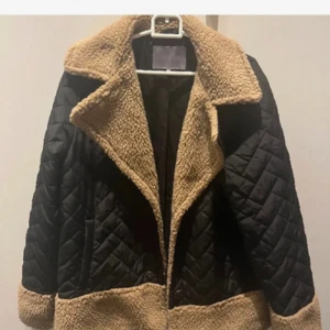 Svart teddyjacka från Culture, strl 38 - Säljer en svart quiltad teddyjacka från Culture i storlek 38. Jackan har bred krage och detaljer i beige teddyfleece vid krage, nederkant och ärmslut. Snygg loose passform och perfekt för höst och vinter. 