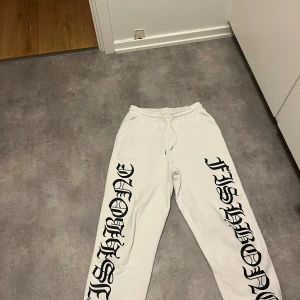 Vita mjukisbyxor med tryck från Fishbone - Vita mjukisbyxor från Fishbone med stora svarta tryck längs båda benen. Har tyvärr en liten fläck som inte går bort i tvätten.