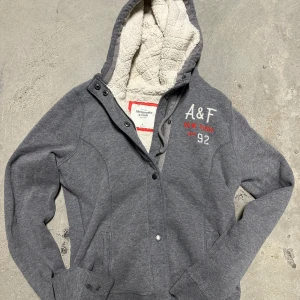 Abercrombie hoodie med fodring och knappar - Säljer nu denna extremt eftertraktade och sällsynta Abercrombie hoodie med fodring och knappar! Grymt skick, inga defekter - ser exakt ut som på bilderna! Storlek M! Skriv gärna vid frågor 💬✌️