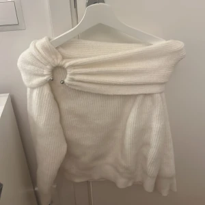 Vit offshoulder stickad topp - Säljer en vit stickad offshoulder topp med snygg detalj i form av en ring framtill. Perfekt till julen!