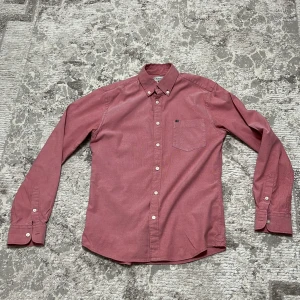 Rosa Oxfordskjorta från Lexington - Snygg rosa Oxfordskjorta från Lexington i klassisk passform. Skjortan har button-down krage, bröstficka med liten Lexington-logga och vita knappar. Tillverkad i mjuk bomull, perfekt för dig som gillar stilrena och tidlösa plagg.