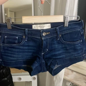 Mörkblå jeansshorts från Abercrombie & Fitch - Snygga mörkblå jeansshorts från Abercrombie & fitch💕. Den har inga defekter och säljs då dem är oanvända. De har en lågmidjad passform och är i storlek 24☺️. Priset går att diskutera vid snabbt köp💕.