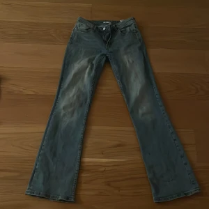 Blå bootcut jeans från C XS/32 - Snygga blå jeans från C i storlek XS/32 med klassisk bootcut-modell. Jeansen har en ljus tvätt och raka ben som blir vidare nedtill. Tillverkade i jeansmaterial med femficksdesign och bälteshällor. Perfekta för dig som gillar retrovibbar och avslappnad stil.
