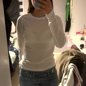 Vit långärmad tröja i bomull - Säljer en enkel och fräsch vit långärmad tröja i mjuk bomull. Modellen är slim och har rund halsringning, perfekt att matcha med jeans eller under en jacka. Passar dig som gillar stilrena och basic plagg.