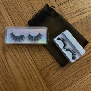 Två par lösögonfransar i svart - Säljer två par svarta lösögonfransar i olika stilar, en med extra volym och en mer naturlig look. Kommer i praktiska plastförpackningar och med en svart förvaringspåse. Perfekt för att lyfta din sminkning till nästa nivå.