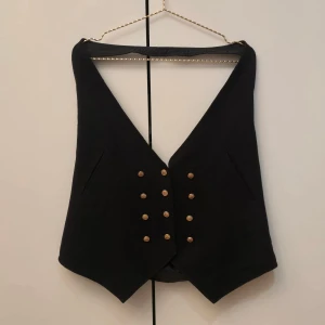 H&M prydlig kostymväst - 🌷FÖRST TILL KVARN!🌷 Svart kostymväst från h&m. Köpte den secondhand när jag skulle klä ut mig till en pirat i gymnasiet. Hade den öppet med en frillig skjorta under, som Jack Sparrow⚓️🛶🥃 den är ganska stor i storleken, vet inte vad det är för storlek kanske M eller L? Det kanske är man storlek på denna kan ge mått vid intresse.. Superfin under ett kavajset eller tuxedo för fest. 12 guldknappar i fram och 2 i bak. VILL BLI AV MED ASAP!