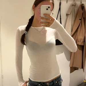 Vit långärmad slim tröja - Säljer en tunn och figurnära vit långärmad tröja med rund hals. Tröjan är genomskinlig och har en enkel, clean look som passar perfekt till jeans eller kjol. Materialet känns lätt och stretchigt, vilket gör den skön att bära. Perfekt för dig som gillar minimalistisk stil.