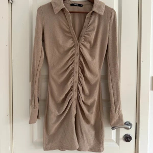 Beige skjortklänning från Bik Bok  - Snygg beige skjortklänning från Bik Bok i storlek XS. Klänningen har lång ärm, krage och knappar hela vägen framtill. 