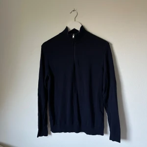 Mörkblå half zip-tröja från Selected Homme - Mörkblå långärmad tröja från Selected Homme med half zip och hög krage. Tillverkad i 100% bomull för en skön och lätt känsla. Enkel och stilren design som passar perfekt till lager-på-lager under höst och vinter. 4F10