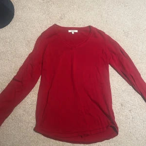 Röd långärmad tröja från Soaked - Säljer en enkel och snygg röd långärmad tröja. Tröjan har v-ringad hals och är i ett mjukt bomullsmaterial. Perfekt för dig som gillar en klassisk och stilren look.
