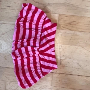 Randiga shorts från myWear, stl 68 - Säljer ett par söta shorts från myWear i storlek 68. De är rosa och röda med breda ränder och har en bekväm resår i midjan. Perfekta för varma dagar och riktigt mjuka mot huden.