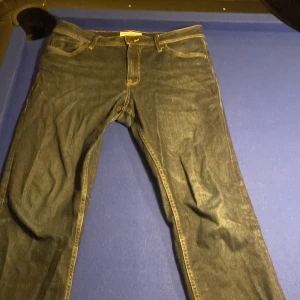 Mörkblå jeans från Stock & Hank W32 L32 - Snygga mörkblå jeans från Stock & Hank Supply Company i klassisk rak modell. Jeansen har kontrastsömmar, fem fickor och är tillverkade i slitstarkt denimtyg. Perfekt passform för dig som gillar stilrena och tidlösa jeans.