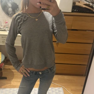 Grå tröja från H&M - Superfin grå långärmad tröja med deraljer på ena axeln. Lite croppad nertill