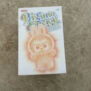 Bigmo Energy Plush Pendant Blind Box - Bigmo Energy Plush Pendant Blind Box från Pop Mart. Oöppnad förpackning med chans att få en av flera söta figurer, inklusive hemlig utgåva. Perfekt för samlare och som present. Kartongen är i nyskick utan synligt slitage eller defekter.