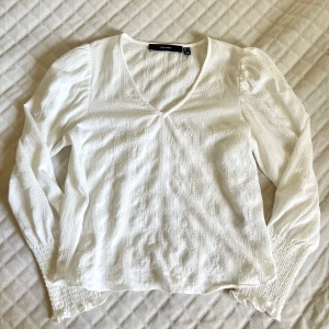 Vit v-ringad blus vero moda - Använd endast 1 gång!  Volanger vid axlarna samt en längre mudd nere på ärmarna   98% POLYESTER  2% ELASTAN 
