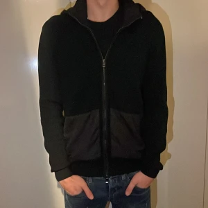 Cardigan - En riktig snygg svart cardigan med avtagbar luva, skick nästan som ny inga defekter. Ny pris cirka 2000. Perfekt nu när de börjar bli lite kyligt! 