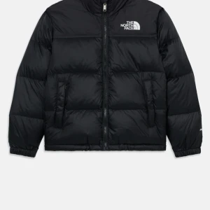 Svart dunjacka från The North Face - Säljer en svart dunjacka från The North Face i storlek L. Jackan har en klassisk puffer-design med hög krage, två sidofickor med dragkedja och logga på bröstet. Perfekt för kalla dagar och har en snygg, enkel look.