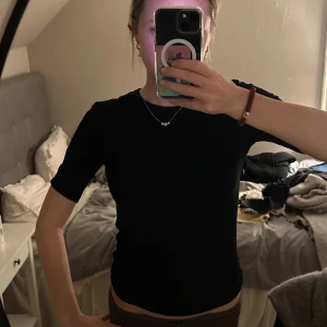 Svart topp med öppen rygg  - Svart topp från Zara med halvlånga ärmar och snygg öppen rygg med knytband. Modellen är slim och har en enkel, stilren look framtill medan ryggen har en cool cut-out detalj. 