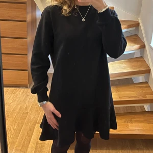 Svart volangklänning från Threadbare - Svart kortklänning från Threadbare med rund hals och långa ärmar. Klänningen har en loose passform och avslutas med en bred volang nedtill. Passar perfekt till höst och vinter🤎