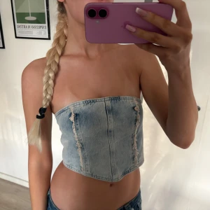 cool jeanstopp  - Cool ljusblå croppad tubtopp i denim från h&m med snygga slitna detaljer framtill och knappar i ryggen.