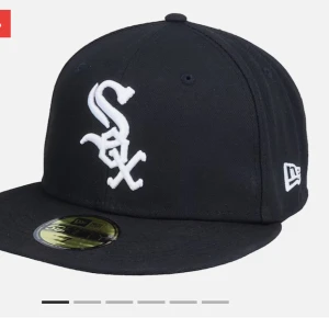 Svart New Era White Sox keps - Snygg svart keps från New Era med Chicago White Sox-logga broderad i vitt framtill. Klassisk 59FIFTY-modell med platt skärm och broderade ventilationshål. MLB-logga baktill och New Era-logga på sidan. Tillverkad i bomull för en bekväm passform.