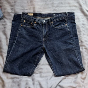 Levi's 502 mörkblå jeansbyxor - Säljer ett par Levi's 502 jeans i mörkblå tvätt med klassiska fem fickor och snygga kontrastsömmar. Modellen har rak passform och är tillverkad i slitstarkt jeanstyg. Perfekt för dig som gillar tidlös och clean stil.