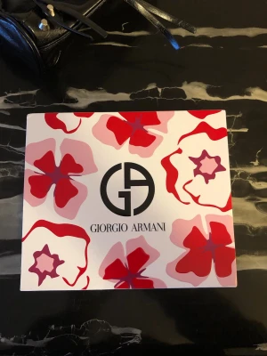 Giorgio Armani presentbox  - Lyxig presentbox från Giorgio Armani med Sì Intense. Innehåller en parfym (100 ml), en mindre parfym (15 ml) och en återfuktande body lotion (50 ml). Boxen har blommigt mönster i rött och rosa och är perfekt som gåva.