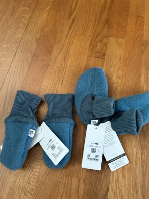 Merinotossor och vantar - Då jag råkat köpa dubbelt säljer jag ett helt nytt sett tossor och vantar i 100%merinoull i strl 1/2 år. Har använt de jag har till min pojk som värmer gott.