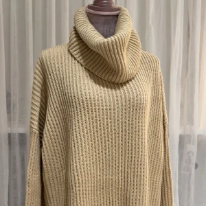 Beige stickad polotröja oversized - Säljer en beige, grovstickad polotröja med oversized passform och bred krage. Tröjan har långa ärmar och ett ribbat mönster och har slits på båda ändorna.