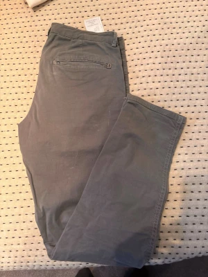 Grå cargopants från Dondup - Säljer ett par grå cargopants från Dondup med raka ben och praktiska fickor på sidorna. Byxorna har knappstängning och bälteshällor, tillverkade i mjuk bomull som är skön att ha på sig. Perfekt för dig som gillar en avslappnad och funktionell stil.