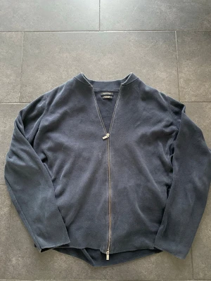 Mörkblå kofta från Massimo Dutti - Säljer en stilren mörkblå kofta från Massimo Dutti med hel dragkedja framtill. Tröjan har långärmad design och är gjord i mjuk bomull som känns skön mot huden. Perfekt för lager-på-lager och enkel att matcha med jeans eller chinos.