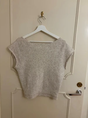 Beige stickad ärmlös tröja - Stickad från Nelly, ena sidan går ner som off shoulder, storlek S