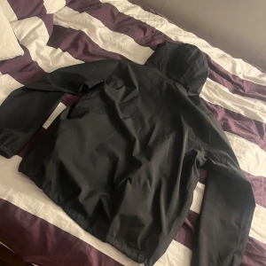 Svart vindjacka från Haglöfs - Säljer en svart vindjacka från Haglöfs med huva och dragkedja. Jackan har en stilren design och är perfekt för blåsiga dagar. Den har långa ärmar och en praktisk ficka framtill. Women l storlek men passar killar som har s/m också! 700kr eller bud