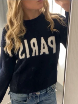 Mörkblå stickad ”Paris” tröja från HM - Säljer denna jättefina mörkblåa stickade tröjan med vit text 'PARIS' framtill💗 Den är från Hm och storleken är xs💞 Den är i jättebra skick och bara använd några fåtal gånger! Skriv gärna vid frågor eller prisförslag❣️ (lånad bild)