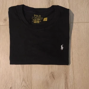 Svart t-shirt Polo Ralph Lauren - Ralph Lauren t-shirt i marinblått i storlek S. Klassisk och tidlös modell med normal passform, enkel att matcha till både vardagliga och mer uppklädda looks. Oanvänd och i nyskick. Tillverkad i 100 % bomull. Rök- och djurfritt hem. Nypris: 1000kr