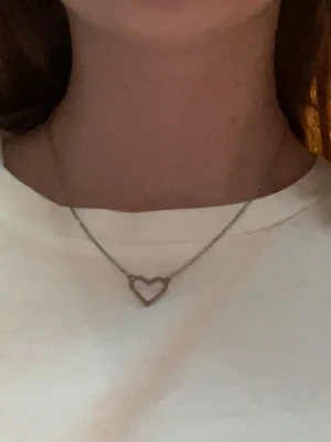 Hjärt halsband  - Silvrigt hjärt halsband. Ganska kort kedja. Den har klarat tvättmaskinen men skulle inte rekommendera att ha den i vatten