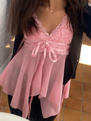 Rosa spettslinne med rosett - Säljer en superfin vintage rosa blus med spets upptill och omlott-design ifrån Ginatricot . Blusen har tunna axelband, v-ringad hals och en söt rosett framtill. Materialet är lätt och luftigt, med transparenta lager och dekorativa band. Man kan ha som både nattlinne men också ute. Storlek M men passar Xs och S också 