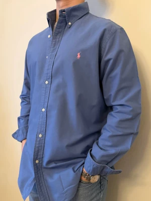 Blå Ralph Lauren skjorta - En stilren skjorta från  Ralph Lauren. Second hand men i väldigt fint skick ✨ Tvättad och struken – redo att användas direkt.  Perfekt för alla årstider, funkar både uppklätt och casual. Inga defekter och loose fit.  Storlek 👔: L  (något längre och vidare i modellen) Nypris 💰: ca 1 300 kr 