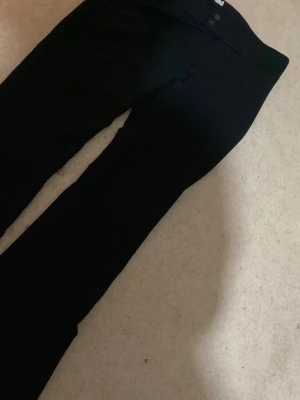 Svarta bootcut byxor med låg midja - Säljer ett par svarta byxor med bootcut-modell och hög midja. Byxorna har en klassisk look med två knappar i midjan och är tillverkade i ett mjukt material . Passar perfekt till er som gillar att ha på sig sköna kostymbyxor t.ex till jobb eller skola vart som helst funkar💞