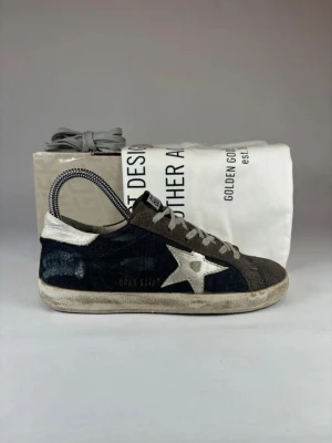 Golden Goose sneakers - (Nypris 4900kr)Säljer ett par äkta Golden Goose sneakers skorna kommer med original box, original dustbag och golden goose extra snören. mörkblåa och grått med vit stjärna på sidan. Skorna har snörning, rund tå och är tillverkade i mocka och skinn. Klassisk GGDB-logga på plösen och slitna detaljer för en cool, vintage look.(Size 36 men passar även 36,5)