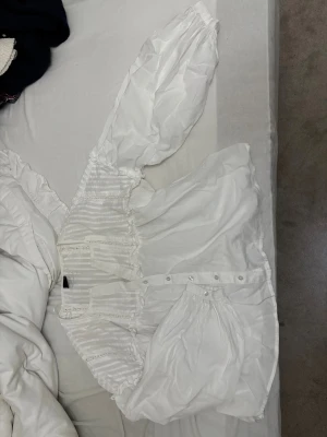 Vit romantisk blus med puffärm - Supersöt vit blus med breda puffärmar och knappar framtill. Blusen har fina spetsdetaljer och transparenta partier på överdelen. Tillverkad i ett lätt, luftigt tyg som ger en romantisk känsla. Perfekt för dig som gillar vintage vibes och unika detaljer. Xs från Gina Tricot. Relativt ny men kommer inte till användning.