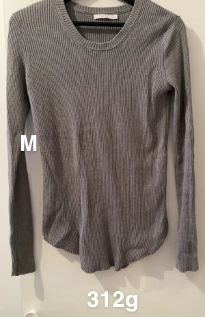 Grå ribbad långärmad tröja M - Snygg grå långärmad tröja i ribbad design, perfekt för dig som gillar enkel och stilren look. Tröjan har rund halsringning och är figurnära i passformen. Passar till både jeans och kjol för en chill vibe.🌸Fint använt skick. Storlek M