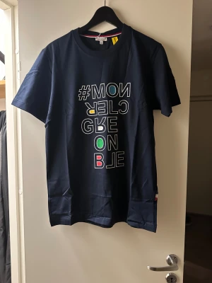 Mörkblå Moncler t-shirt med tryck - Snygg mörkblå t-shirt från Moncler med färgglatt grafiskt tryck på framsidan. 