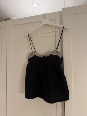 Svart glittrig linnetopp från Zara - Supersnygg svart linnetopp från Zara med tunna axelband och glittriga silverpaljetter längs bysten. Toppen har en lätt puffig form nedtill och är perfekt för att sticka ut. Materialet känns mjukt och lätt, och detaljerna ger en lyxig vibe.