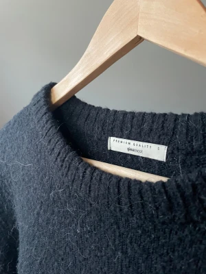 Svart stickad tröja Gina Tricot - Mysig svart stickad tröja från Gina Tricot i storlek S. Tröjan har rund hals och ribbade detaljer vid halsringning, ärmslut och nederkant. Perfekt för kyliga dagar och enkel att matcha med jeans eller kjol.