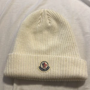 Vit  mössa från Moncler - Vit moncler mössa köpt för 2 år sedan ungefär, den är använd ett fåtal gånger men har doch en pytte liten röd flack där bak, men som nästan är omärkbart att se