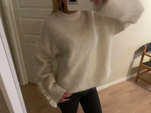 Vit stickad tröja med volang på armen - Superfin vit stickad tröja med volang längs med armen. Endast använd några gånger. Nypris: 990kr